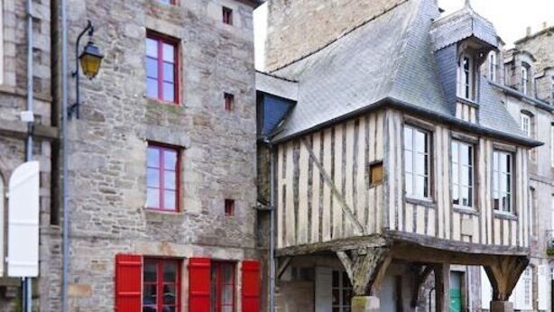Un bâtiment traditionnel en pierre, avec des volets rouges et une structure à ossature bois.