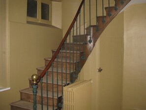 A wooden staircase with a green balustrade and a radiator at the bottom. - La Maison Pavie (Dinan)