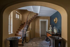 A staircase leading to a door, a radiator, and a statue on a table. - La Maison Pavie (Dinan)