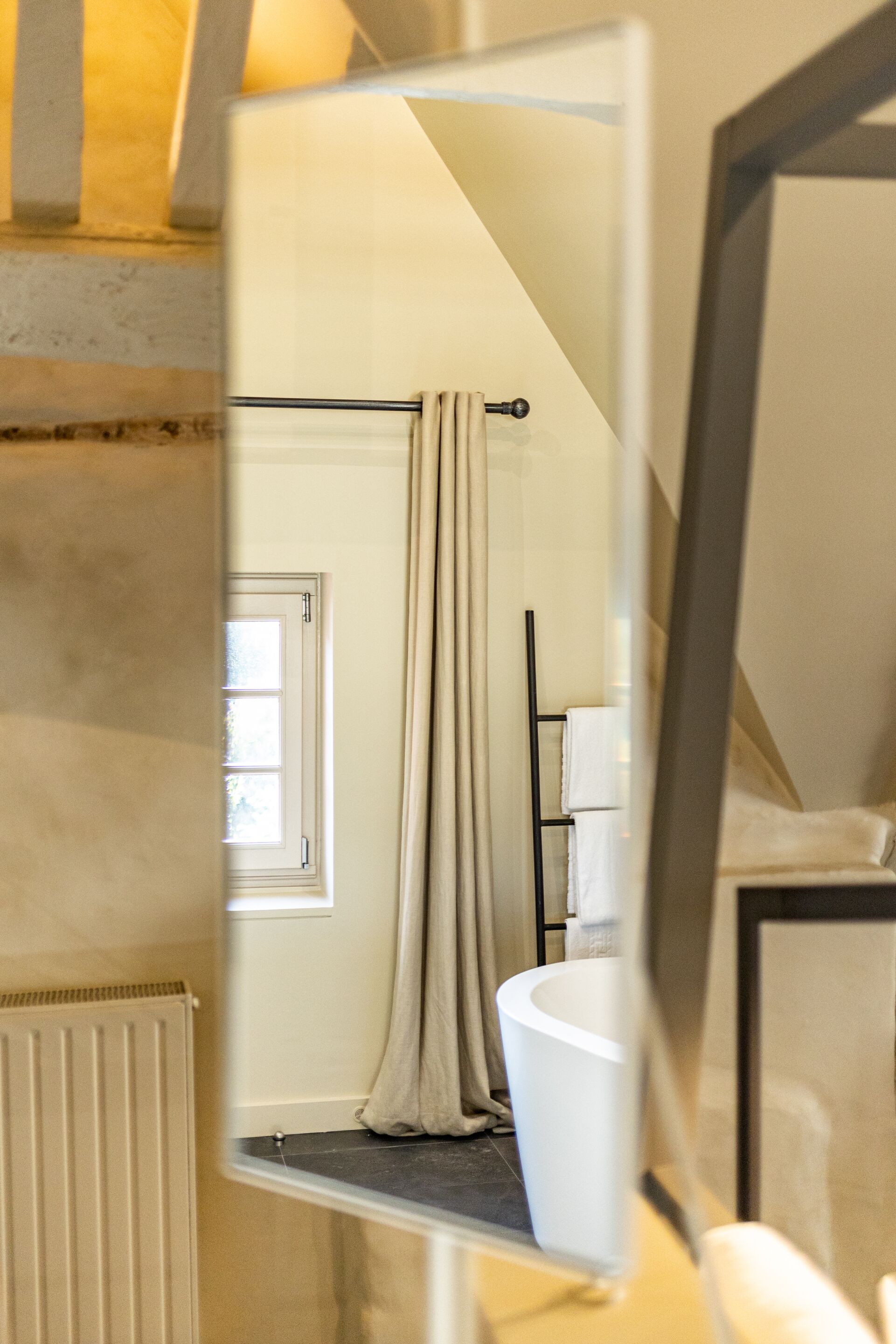A bathroom with a bathtub, a towel rack, and a window.