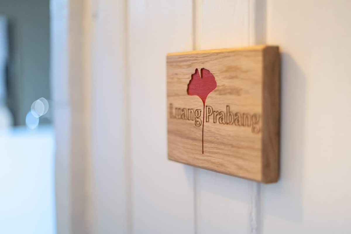 A wooden plaque with the text "LangPrabang" and a stylized red leaf design.