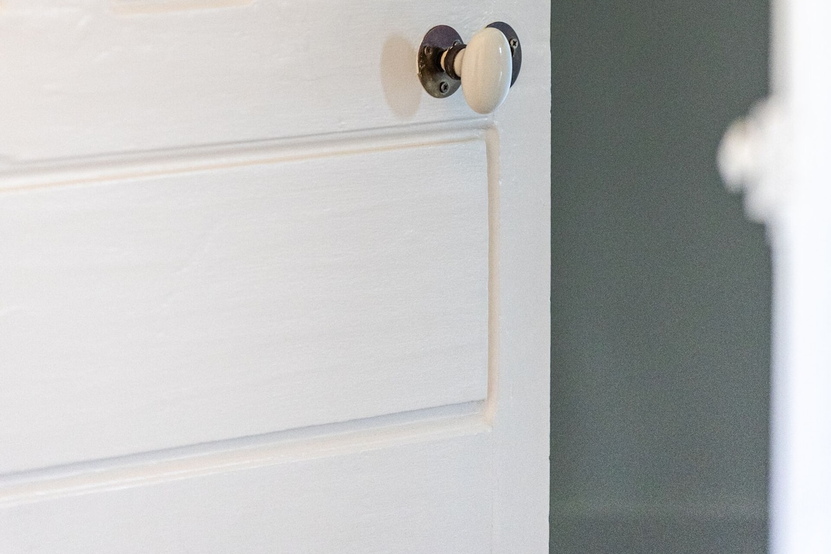 A white door with a wooden plaque and a round doorknob.