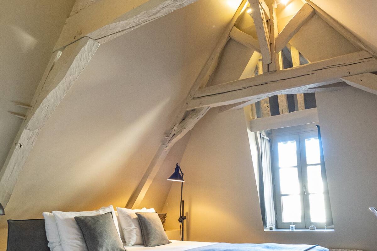 A bedroom with a large bed, a window, and exposed wooden beams.