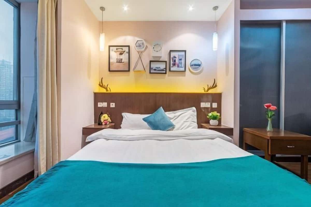A hotel room with a bed, bedside tables, a window, and wall-mounted artwork.