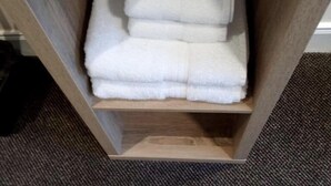 A wooden shelf with folded white towels and two Lux branded containers. - Waverley Inn (Dingwall)