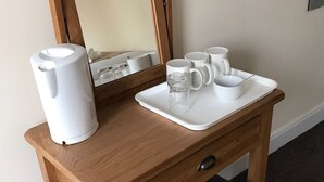 A wooden desk with a white tray holding a white electric kettle, a glass, and several white mugs. - Waverley Inn (Dingwall)