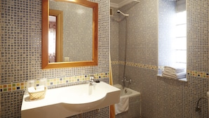 Une salle de bain avec un lavabo, un miroir, une douche et des murs carrelés.
