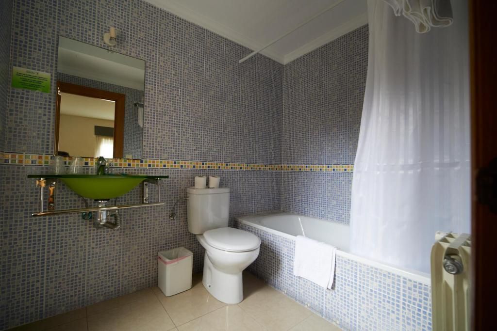 Un baño con inodoro, lavabo, bañera y cortina de ducha.