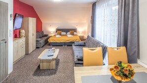 Una habitación de hotel moderna con cama, sofá y zona de comedor.