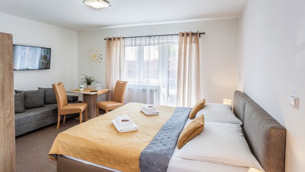 Una habitación de hotel moderna con una cama, un sofá, una mesita y una silla.