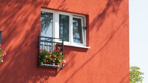 Un edificio rojo con una ventana y un pequeño balcón lleno de flores.