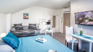 Una habitación de hotel moderna con cama, escritorio, televisor y kitchenette.
