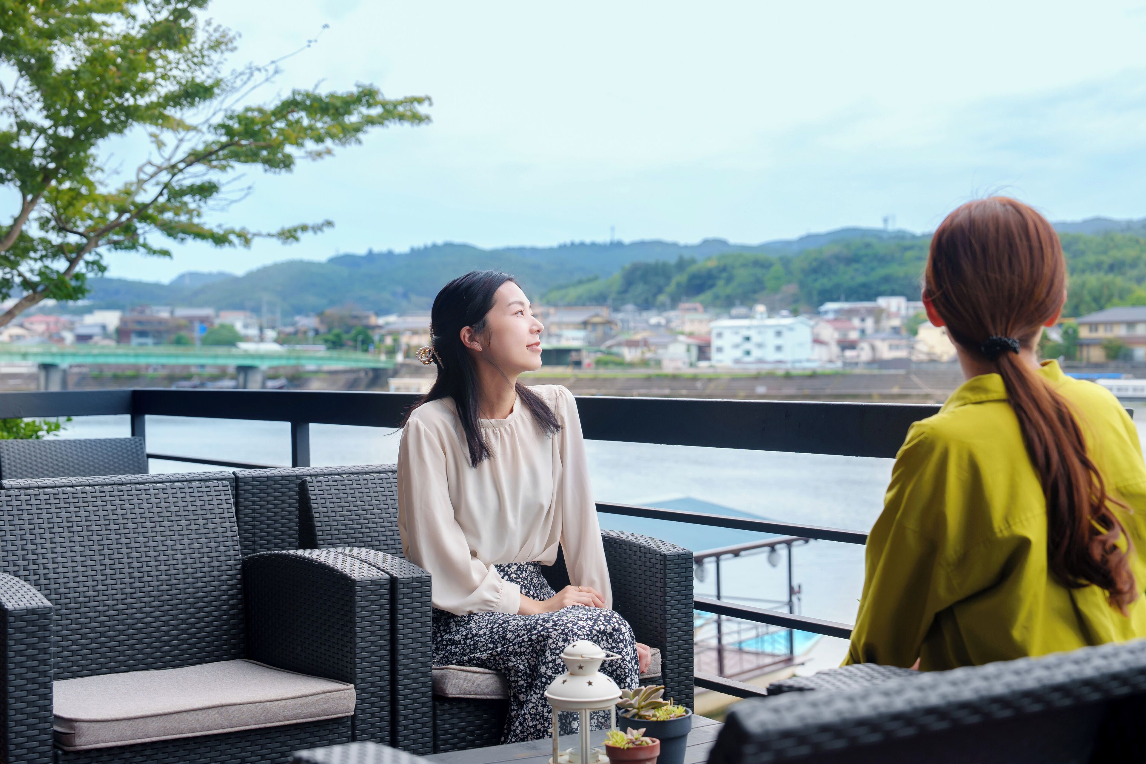 A seating area with wicker furniture and a view of a river and hills.