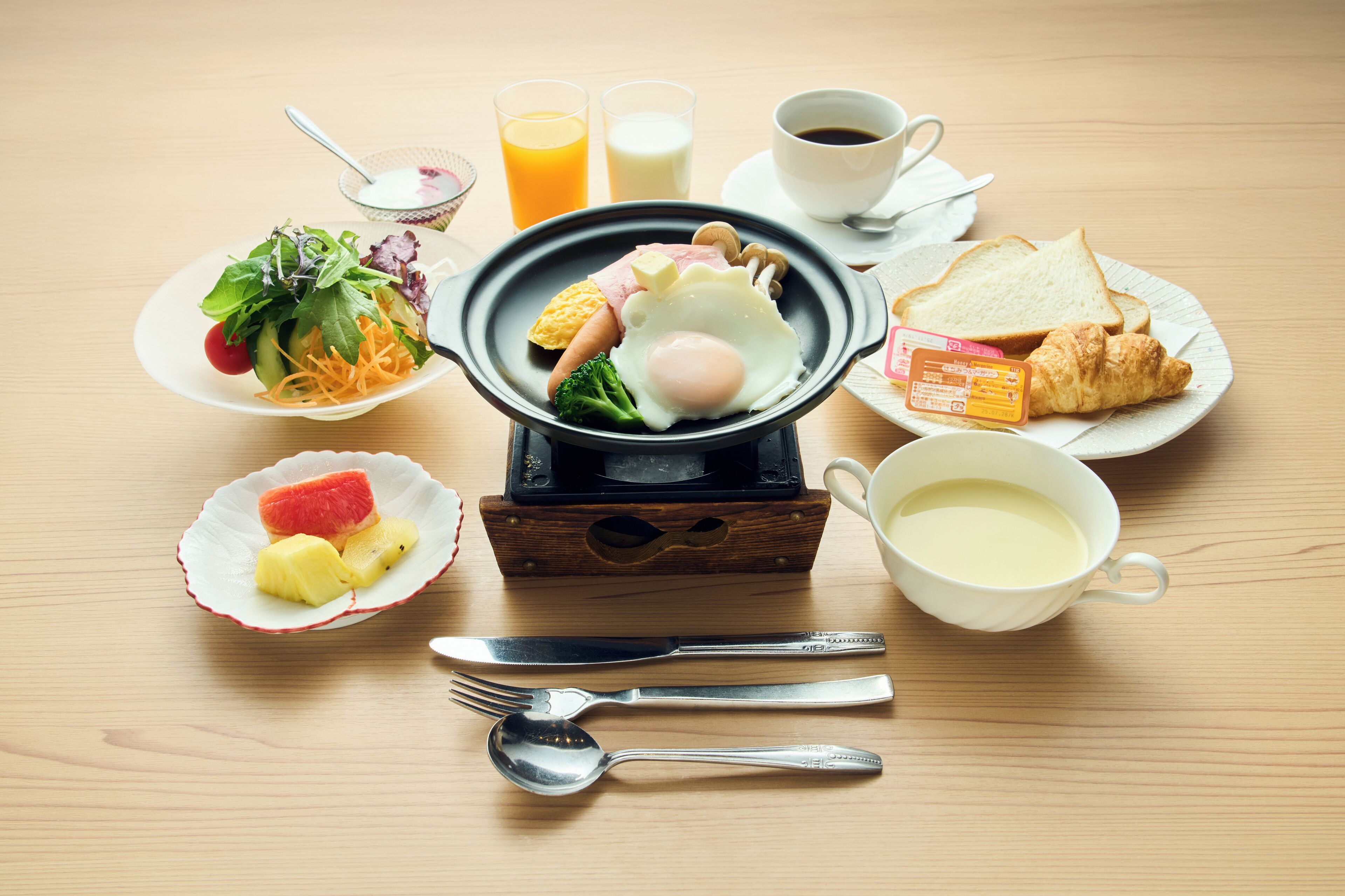A breakfast setting with a hot plate, plates of food, and a cup of coffee.