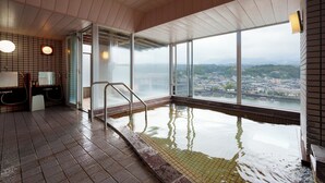 An indoor swimming pool with a view of a cityscape through large windows.