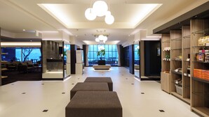 A spacious lobby with a central seating area, a reception desk, and a view of the outdoors.