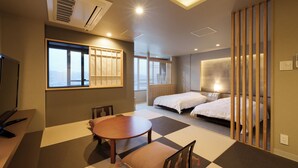 A hotel room with a large bed, a desk, a chair, a table, and a view of the city.