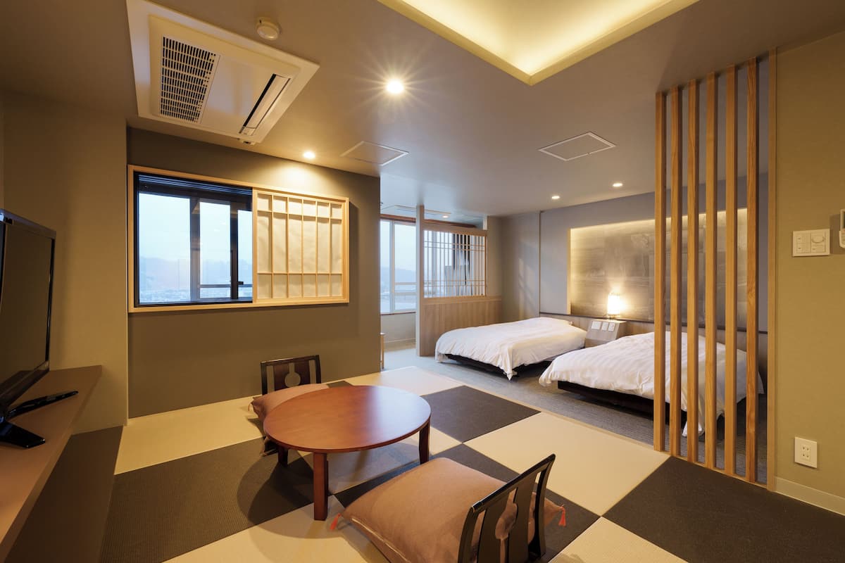 Een hotelkamer met een groot bed, een bureau, een stoel, een tafel en uitzicht op de stad.