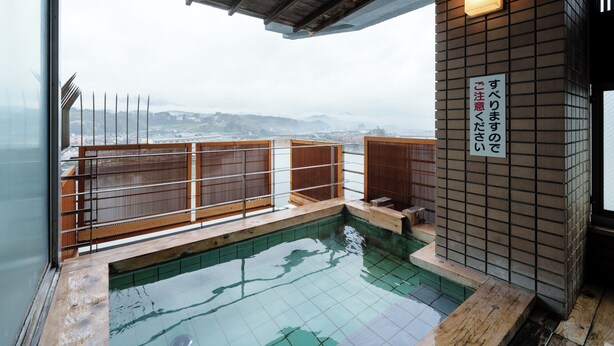 A traditional Japanese onsen with a wooden deck and a view of distant mountains.