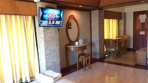 Una habitación de hotel con una cama, un televisor montado en la pared, una mesa redonda con sillas y un espejo.