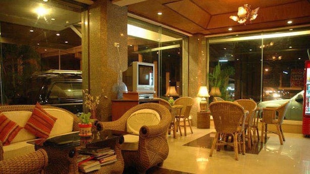 Un vestíbulo con sofá, sillones, una mesa de centro y una televisión.