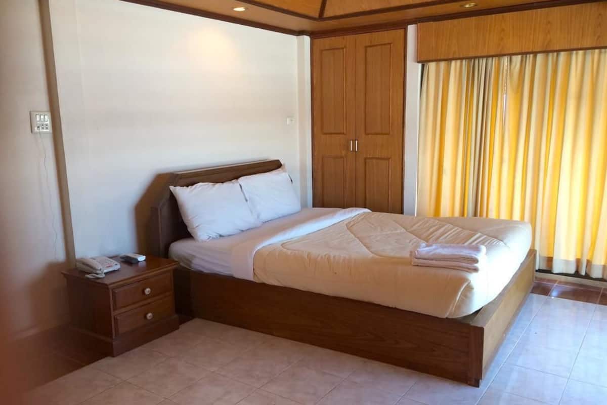 A bedroom with a large bed, wooden headboard, a nightstand with a phone, and a wardrobe.