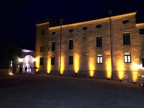 A large, historic building with multiple windows and a stone facade, illuminated by warm lighting. - Villa San Biagio (Colceresa)