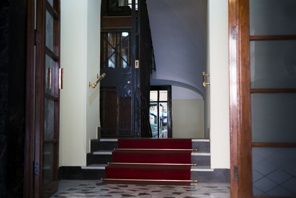A staircase with red steps leading to a dark wooden door. - Suite Cardinale (Rome)