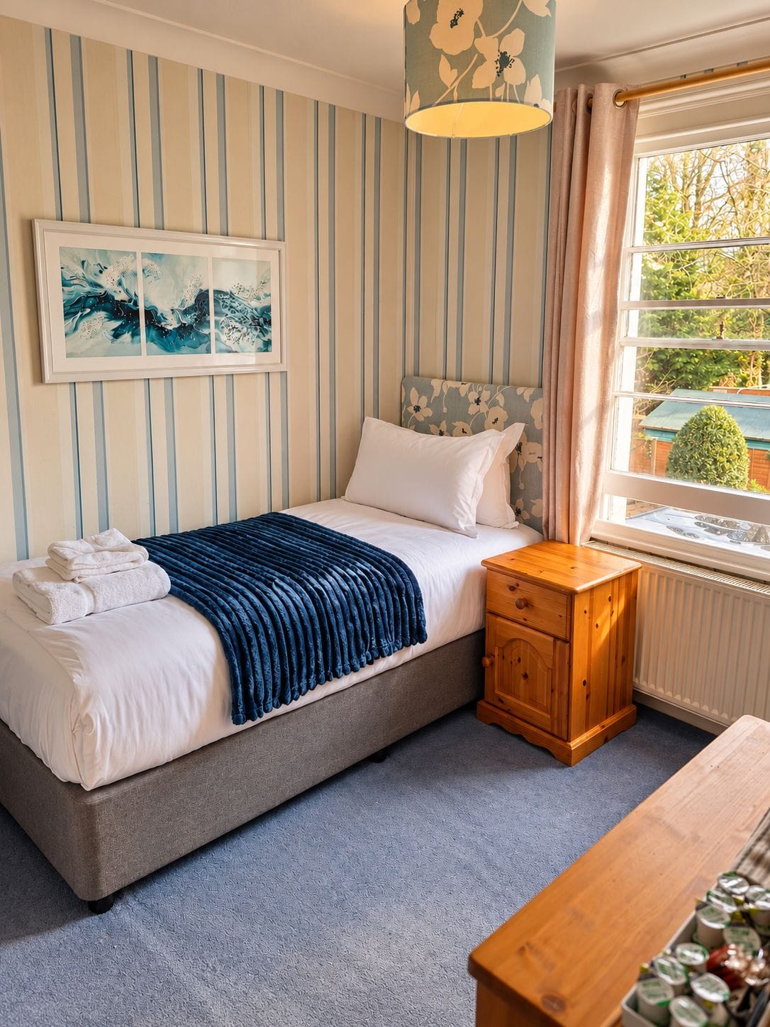 A bedroom with a bed, bedside table, and a window with a view.