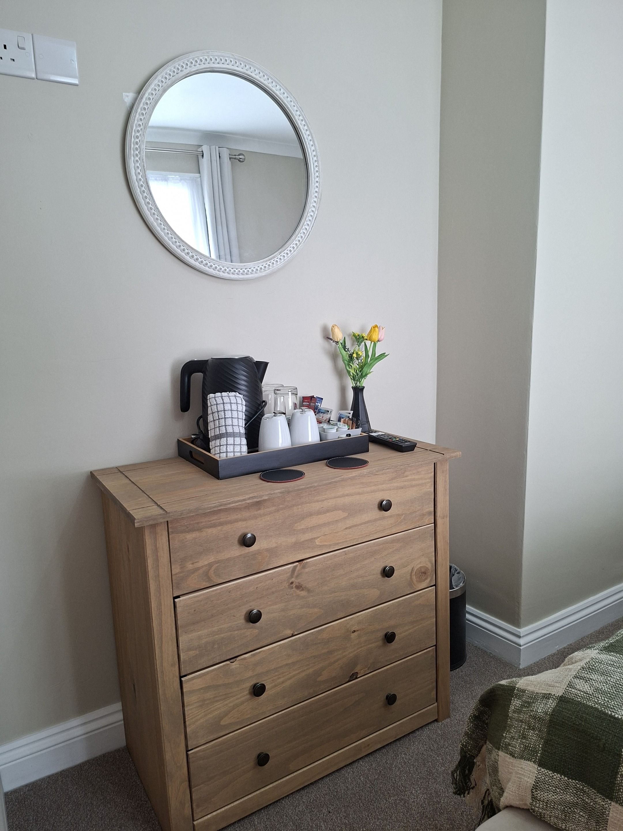 Une commode en bois avec des tiroirs, un miroir et un plateau contenant des articles de toilette.