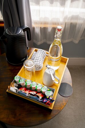 A tray with a bottle of oil, a glass, a jar, a teapot, and a tray of yogurt containers.