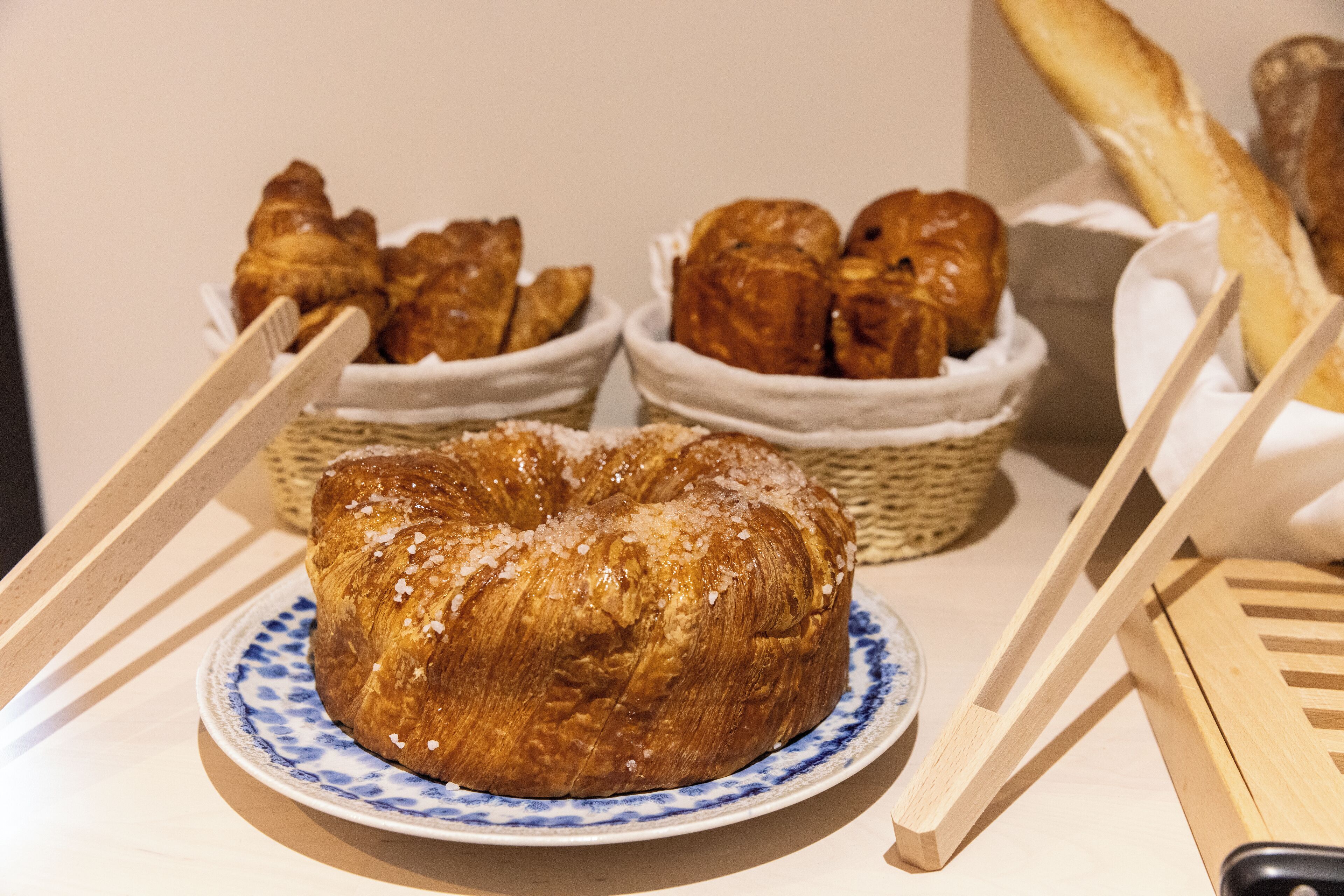 Une table avec une assiette de pain et des paniers remplis de viennoiseries.