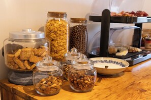 A buffet table with various food items in glass containers, including cookies, cereal, and nuts.