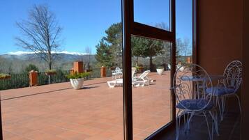 Un patio con mobiliario exterior, vista a las montañas y cielo despejado.