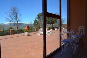 Un patio con mobiliario exterior, vista a las montañas y cielo despejado.
