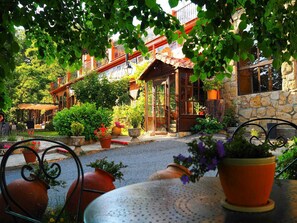 Un patio con un edificio de piedra, plantas en macetas y mobiliario exterior.