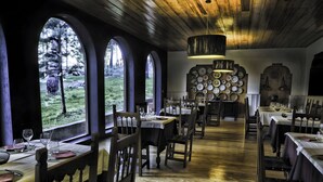 Comedor con varias mesas, sillas y vistas al exterior a través de amplias ventanas.