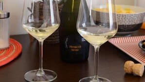 Deux verres à vin sont posés sur une table, à côté d’une bouteille de vin et d’un vase rempli de fleurs.