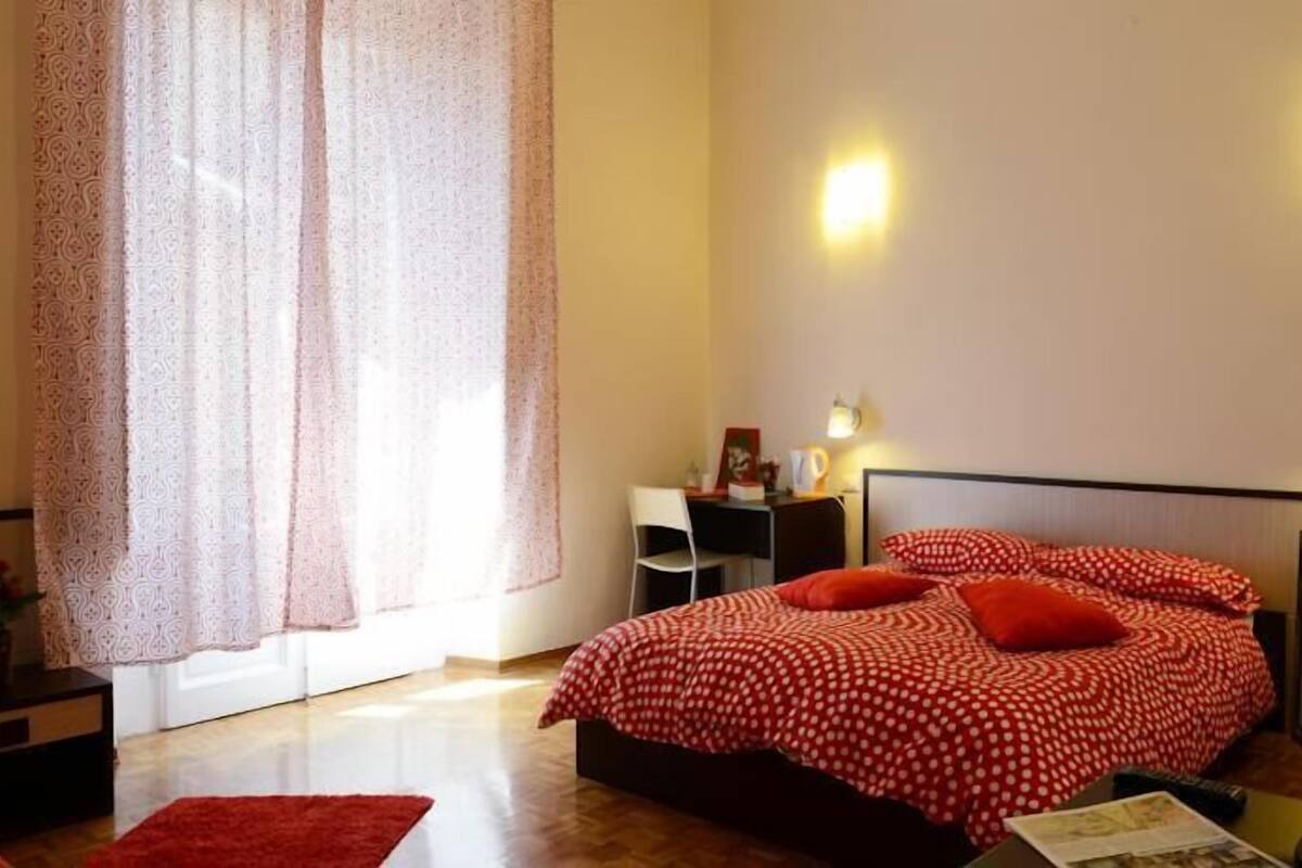 A bedroom with a bed, a desk, a chair, and a television.