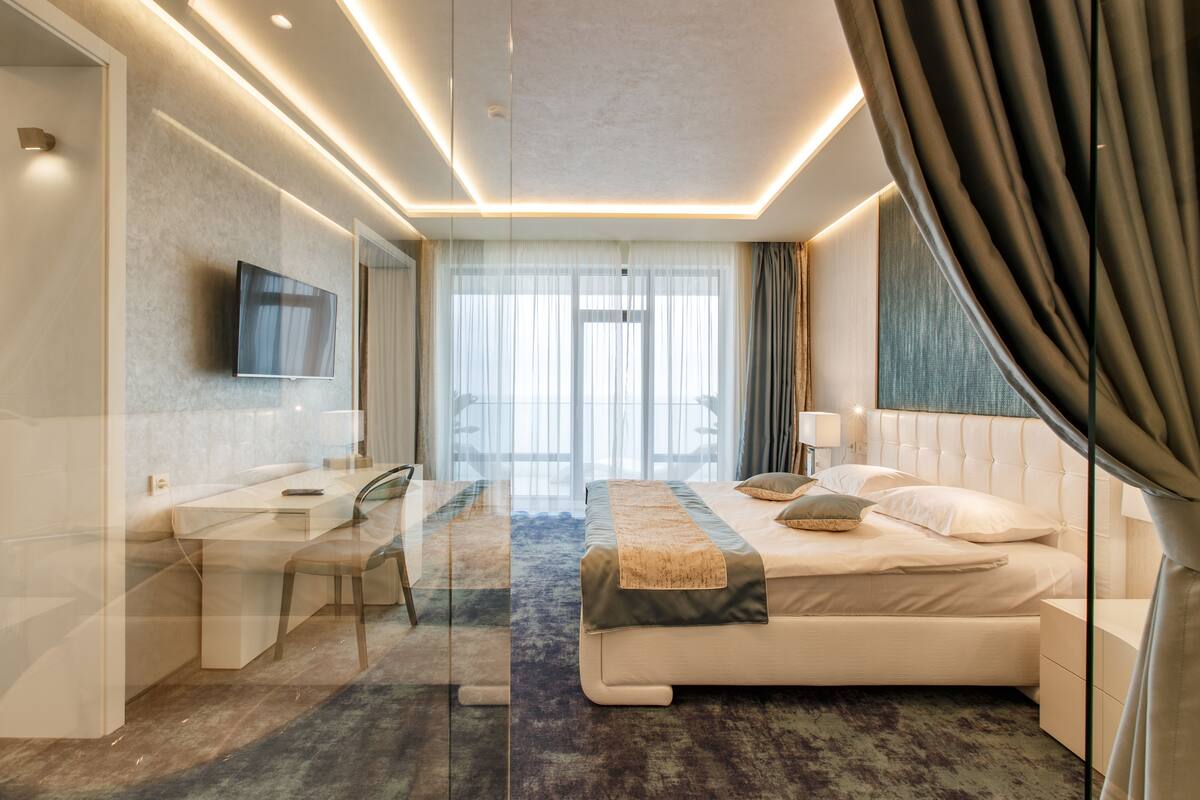 A modern hotel room with a bed, a desk, and a TV.
