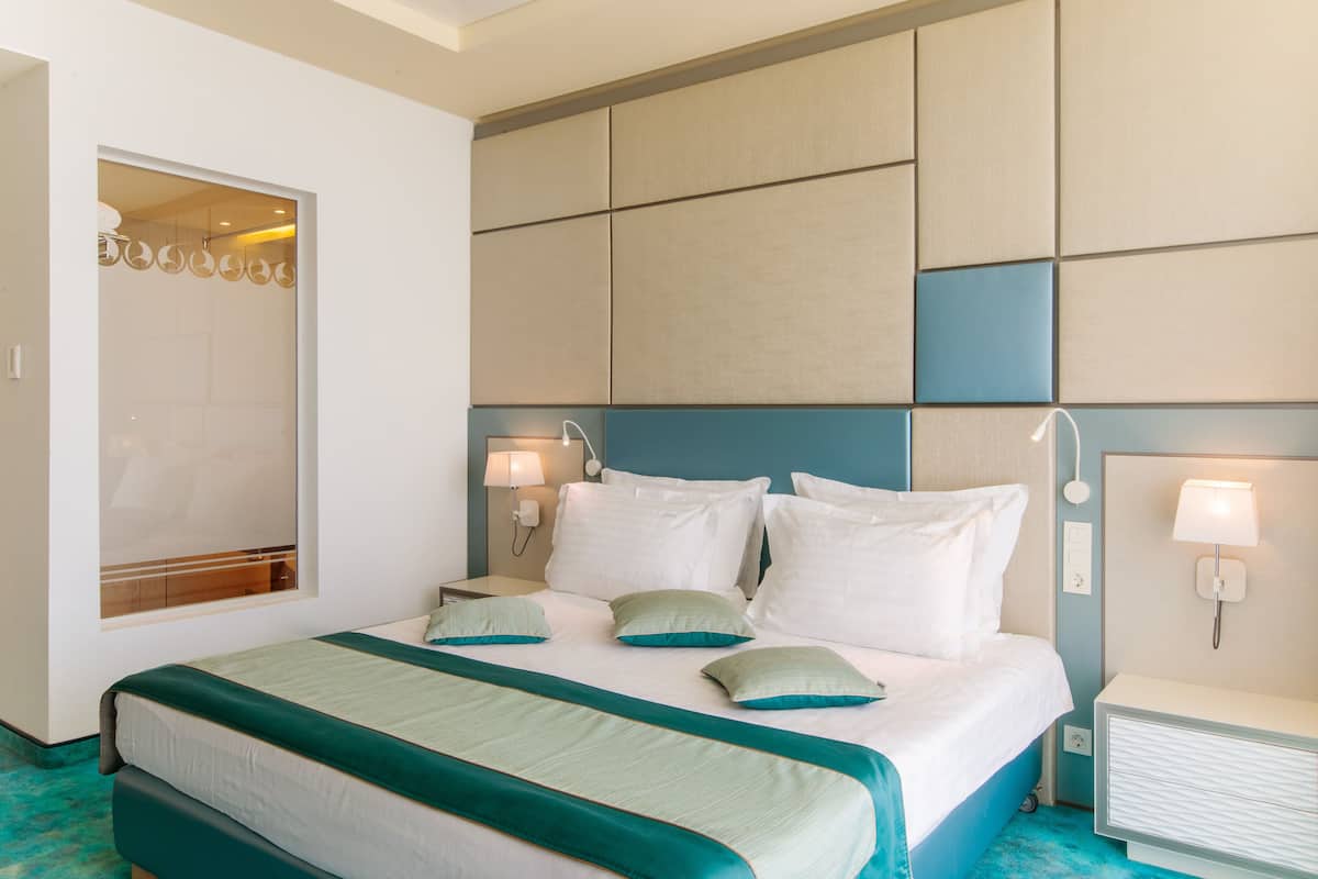 A hotel room with a bed, bedside lamps, a nightstand, and a wardrobe.