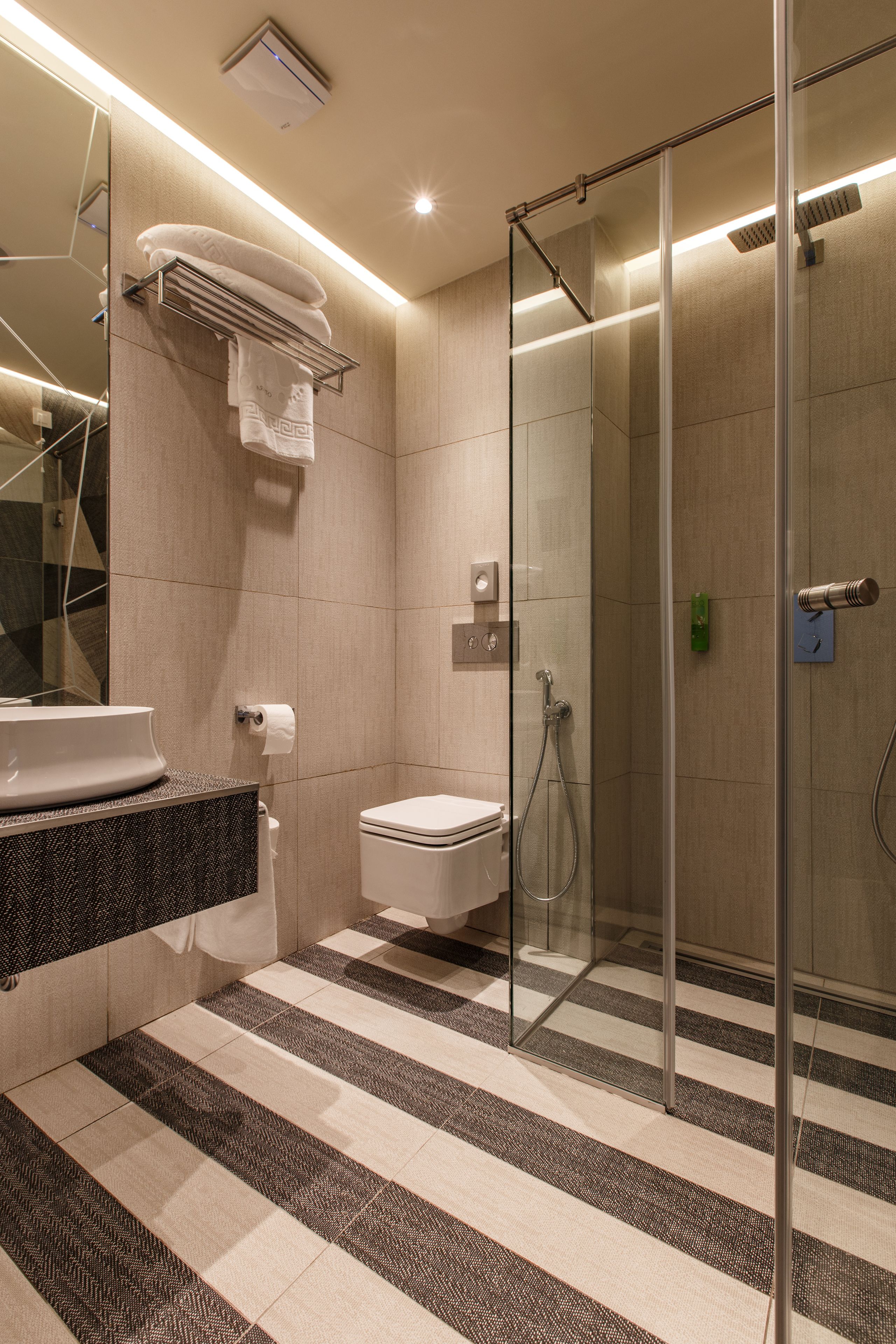 A modern bathroom with a glass shower enclosure, a sink with a dark countertop, and a toilet.