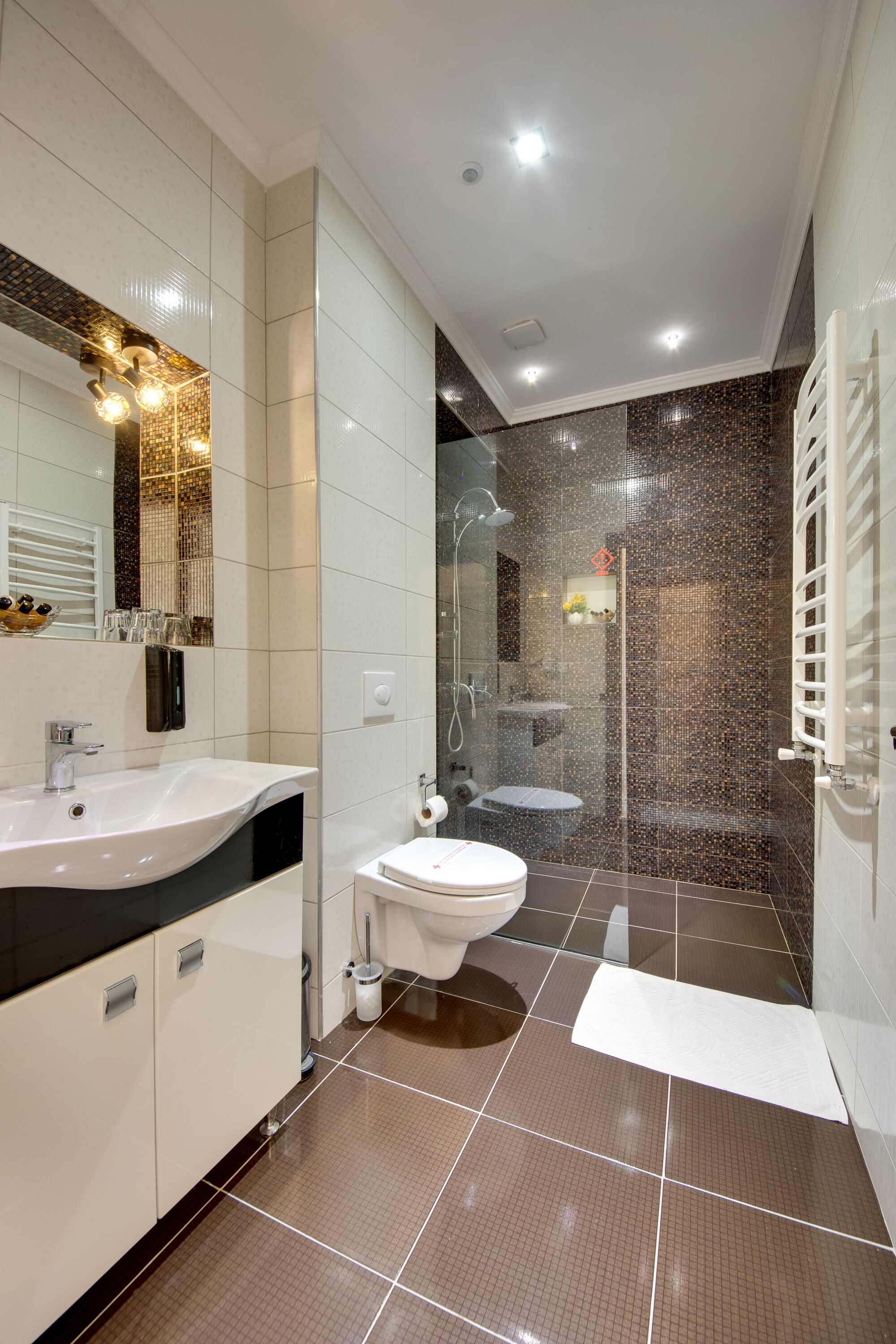 Une salle de bain moderne avec un grand miroir, deux lavabos, une douche et des toilettes.