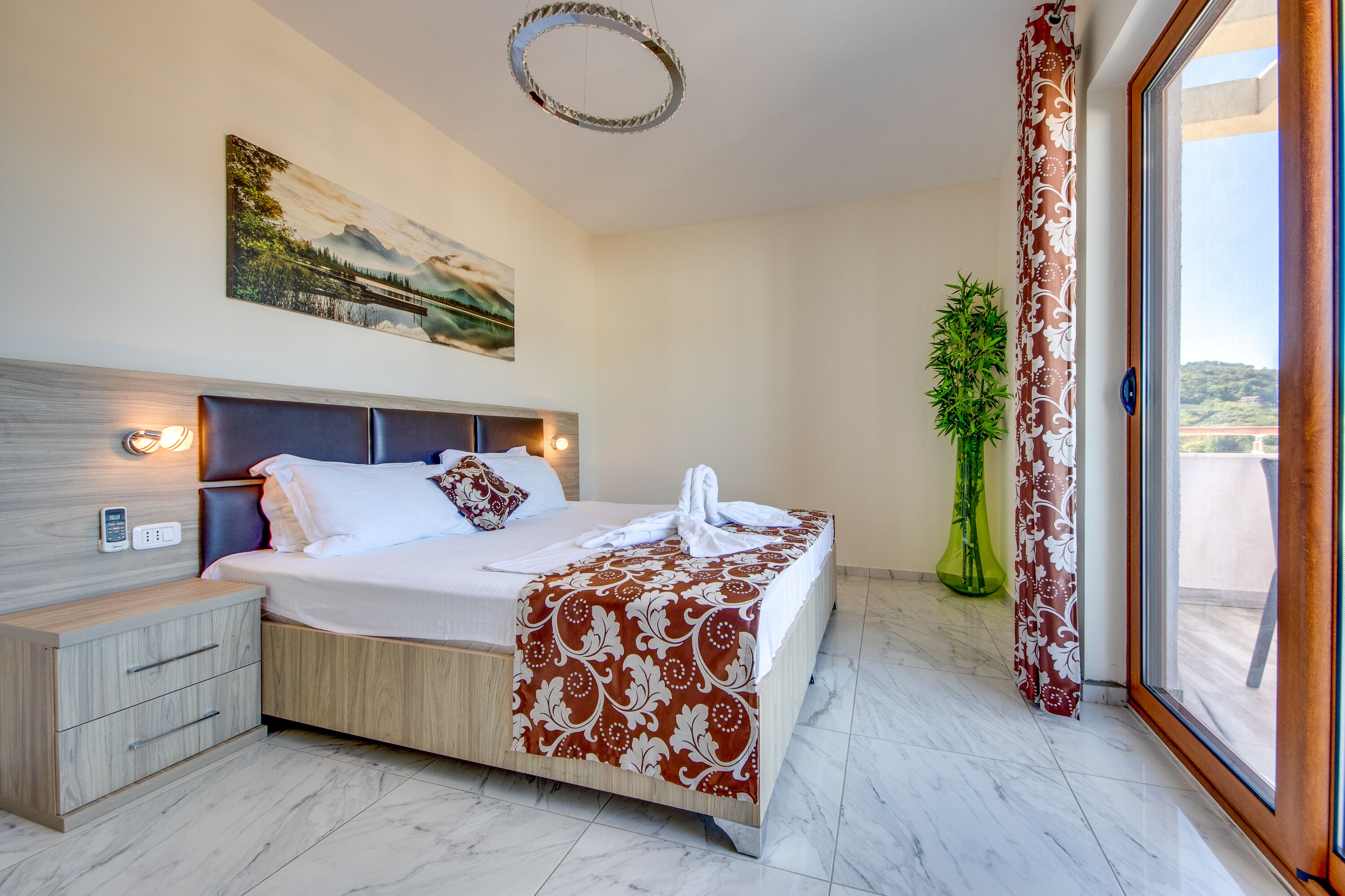 A modern hotel room with a bed, bedside table, and a painting on the wall.