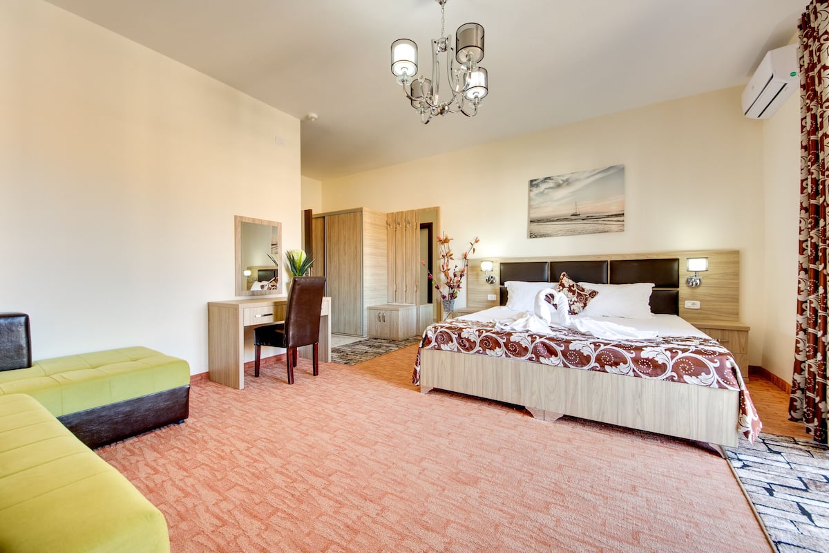 Una habitación de hotel con cama, escritorio, silla y un ventanal grande.