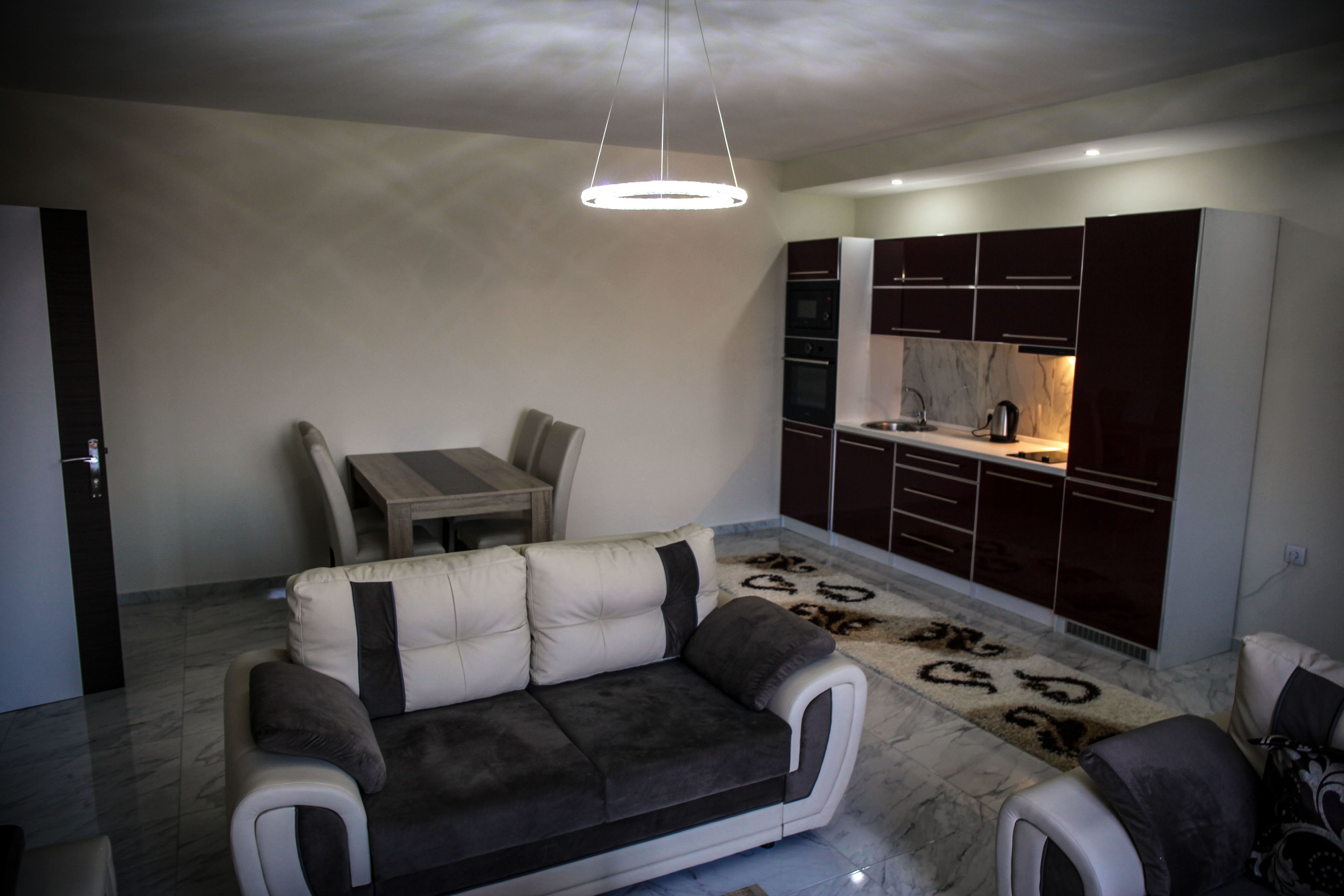 Uma sala de estar moderna com sofá, mesa de jantar e área de cozinha com armários.