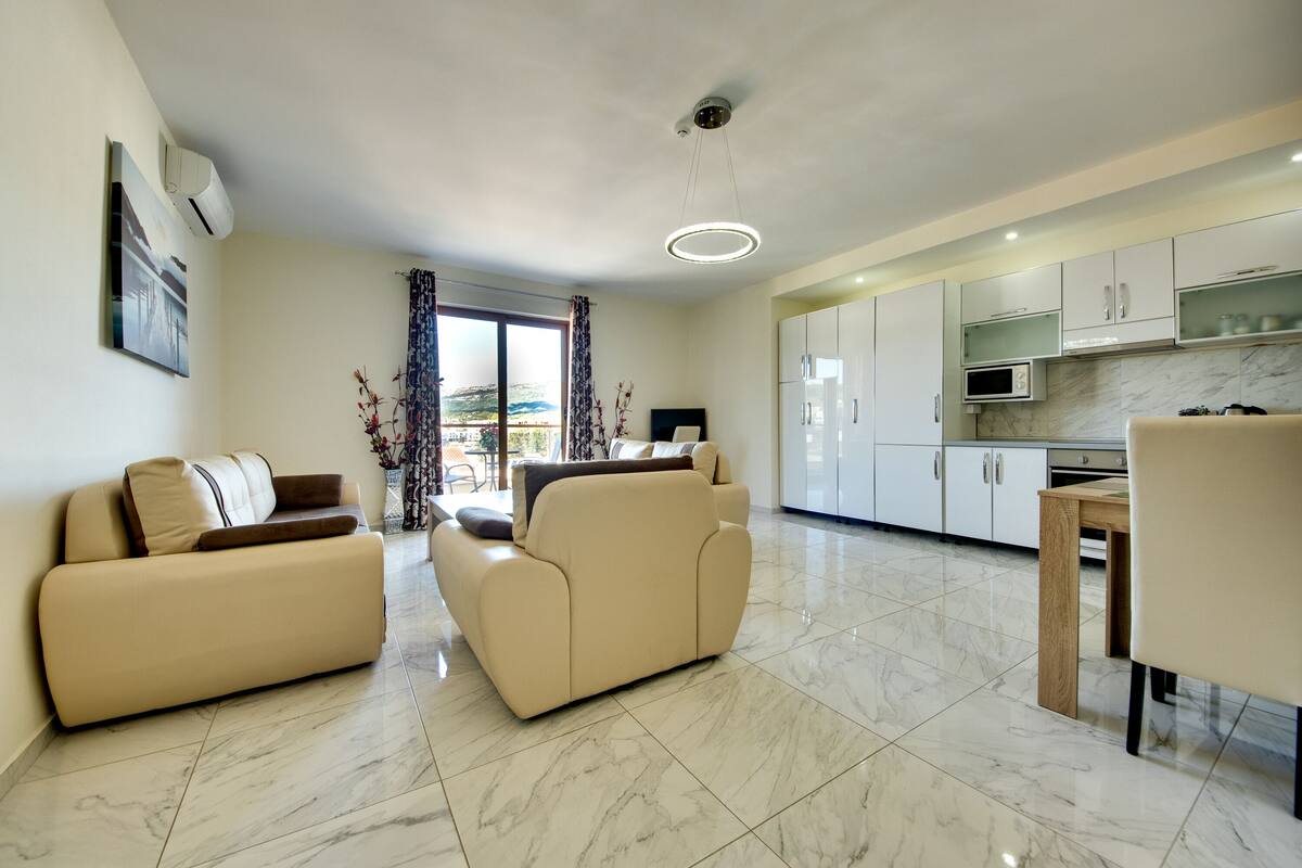Una sala moderna con sofá, una mesa de comedor y una zona de cocina con armarios y un microondas.