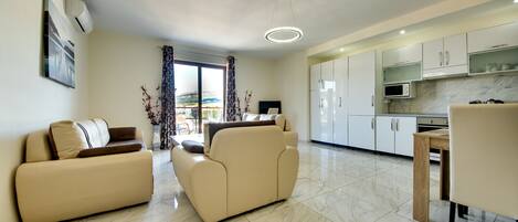 Una sala moderna con sofá, una mesa de comedor y una zona de cocina con armarios y un microondas.
