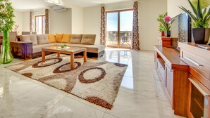A modern living room with a sofa, coffee table, and a TV on a wooden cabinet. - Hotel Montefila (Ulcinj)