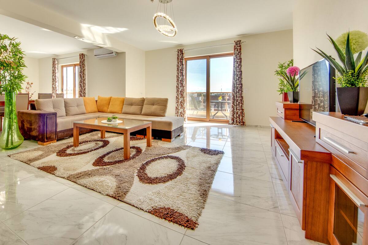 Una sala de estar moderna con un sofá, una mesa de centro y un televisor sobre un mueble de madera.